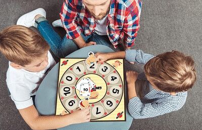 Plateau de jeu Mathsumo autour duquel se trouvent deux enfants et leur papa.